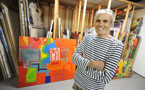 Artist Bill Barrell poses in front of his collection of paintings at his Bullseye Art studios in Easton.
